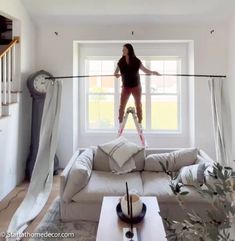 a woman standing on a tightrope in the middle of a living room