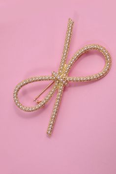 A stunning fusion of sophistication and modern flair. This exquisite accessory features two intricately designed bows adorned with lustrous pearls, creating a captivating statement piece. Product Details:Width: 2.5" Length: 1.5"Metal finish: Gold PlatedProduct: Lead & Nickel CompliantAnti-tarnish: Double E-coating Elegant Gold Bow For Wedding, Elegant Gold Wedding Bow, Elegant Pearl Brooches For Party, Sunglass Chain, Bow Ribbon, Faux Leather Belts, Pearl Brooch, Makeup Storage, Steel Necklace