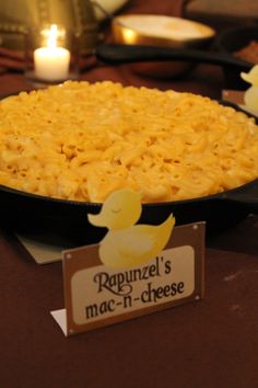 macaroni and cheese is in a pan on a table with candles around it