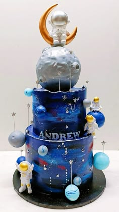 a three tiered cake with an astronaut on top and the moon in the sky