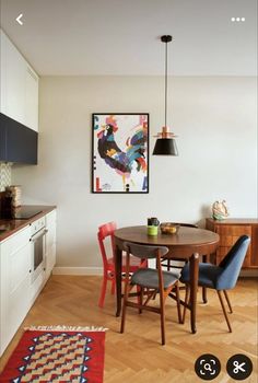 a dining room table with four chairs and a painting on the wall in the background