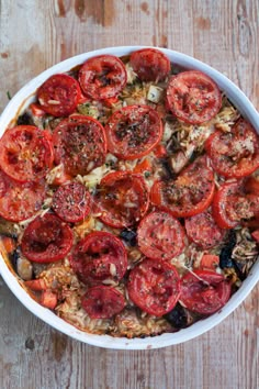 a casserole dish with tomatoes and onions in it on a wooden table top