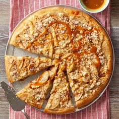 a pizza with caramel toppings on a plate next to a cup of tea