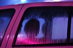 the back window of a pink car with white and red streaks on it's side