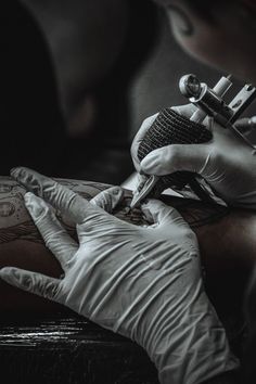 a person getting their arm tattoo done by an artist in white gloves and tattoostands