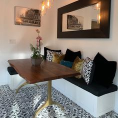 a wooden table sitting under a mirror on top of a white wall next to a bench