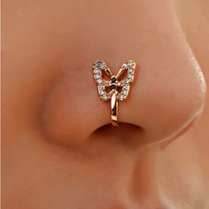 a close up view of a nose with a butterfly ring on it's side