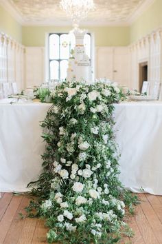 the table is covered with white flowers and greenery