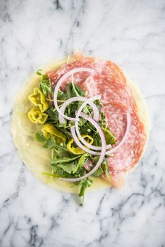 a plate topped with meat and veggies on top of a marble countertop