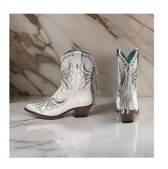 Corral Women's Fringe Inlay Ankle Western Boots in a crisp white color with metallic silver accents. Made with a leather upper, these boots are both stylish and durable, perfect for adding a touch of flair to your outfit. The pointed toe silhouette offers a sleek and sophisticated look, while the interior zip closure ensures easy on and off. The Western heel adds a classic touch, perfect for dressing up any ensemble. Featuring metallic silver inlay accents throughout and silver-toned studded det White High-top Heeled Boots For Fall, White High-top Boots For Fall, White Western Snip Toe Boots, White Western Boots With Snip Toe, White Leather Western Boots, White High-top Boots With Reinforced Heel, White Western Boots With Leather Sole, Western Style White Ankle Boots, White Leather High-top Boots