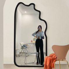 a woman standing in front of a large mirror