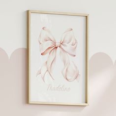 a pink bow is hanging on the wall next to a white frame that says madeline