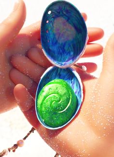 two rings with green and blue swirls on them are being held by someone's hand