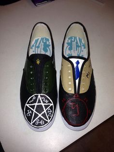 two pairs of shoes with pentagram on them sitting next to each other in front of a white table