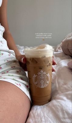 a woman is holding a starbucks drink on her stomach