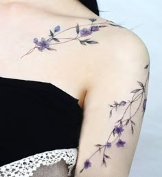 a woman's shoulder with purple flowers on her left arm and the upper part of her right arm