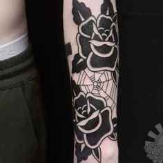 a black and white rose tattoo on the left arm, with an intricate spider web around it