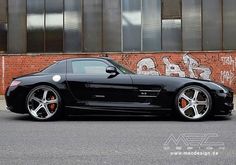 a black sports car parked in front of a brick building with graffiti on the wall