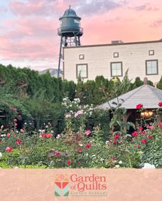 the garden of quilts is full of beautiful flowers and greenery with a water tower in the background