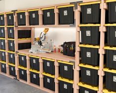 shelves filled with black and yellow bins in a storage room next to a white wall