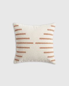 an orange and white striped pillow on a gray background