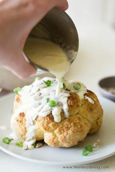 someone is dipping sauce on top of a scalloped biscuit with green onions