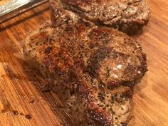 two steaks sitting on top of a wooden cutting board