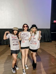 three young women standing next to each other in front of a projector screen wearing t - shirts with words on them