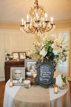 a table with flowers, candles and pictures on it in front of a chandelier