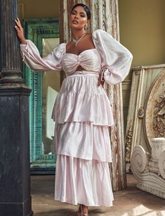 a woman in a white dress standing next to a pillar