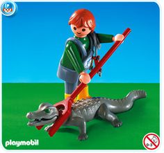 there is a small boy that is playing with a toy alligator on the green ground