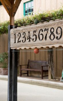 a wooden sign sitting on the side of a road next to a bench and building