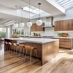 a large kitchen with wooden floors and white counter tops on top of it's island