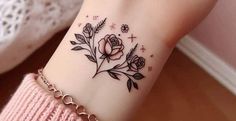 a woman's wrist tattoo with roses and leaves on the side of her arm