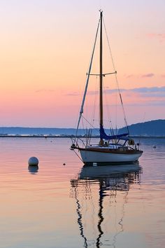 a sailboat floating in the water at sunset