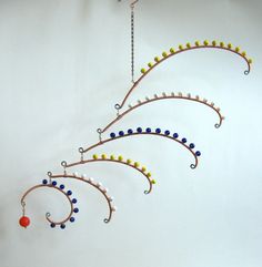 a wind chime hanging from the side of a wall with beads and balls on it