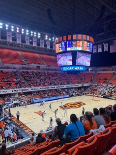 an indoor basketball game is being played on the court with orange seats and people watching