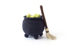 a crocheted pot with a broom and some balls in it on a white background