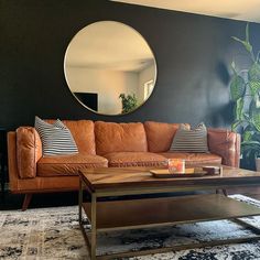 a living room filled with furniture and a large round mirror on the wall above it