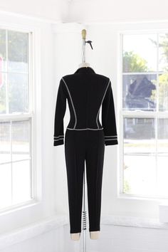 An absolutely killer Tadashi Shoji jumpsuit circa 1980s. She’s got a back zip, mega shoulder with pads, ultra flattering deco black and white piping and stirrup pants! The fabric is very stretchy. Measurements of garment, allow space for fit. Taken flat, doubled for circumference Shown on a size 4 dress form. Modern Size Estimate: 4/6 Measurements do not include stretchBust: 32” Sleeve: 21” outer Shoulder: 17” Waist: 26” Hips: 30” Inseam: 24.5” Rise: 29” Thigh: 10” Ankle: 5” Total length: 50” to Fitted Formal Jumpsuits And Rompers For Winter, Stirrup Pants, Tadashi Shoji, Dress Form, Size 4, Jumpsuit, Like New, Black And White, Pants