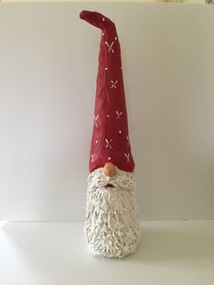 a red and white gnome's hat on top of a white shelf next to a wall