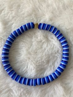 a blue and white striped bracelet on a white furnishing area with a gold plated clasp