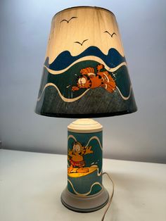 a lamp that is sitting on top of a table next to a light shade with cartoon characters