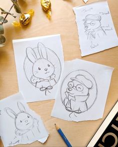 three drawings of cartoon characters on paper next to some chocolate candies and pencils