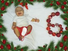 a baby laying on top of a blanket surrounded by christmas decorations