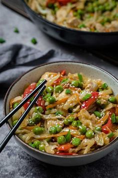 a bowl filled with noodles and vegetables on top of a table next to another bowl