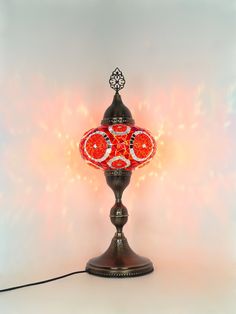 a red lamp sitting on top of a table next to a white wall with lights behind it