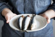 a person holding a plate with three fish on it