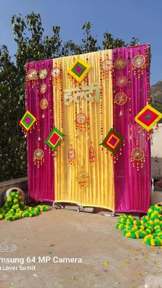 a decorated stage with yellow and pink drapes, green balls and decorations on the ground