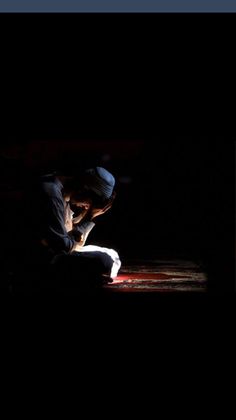 a man kneeling down in the dark reading a book